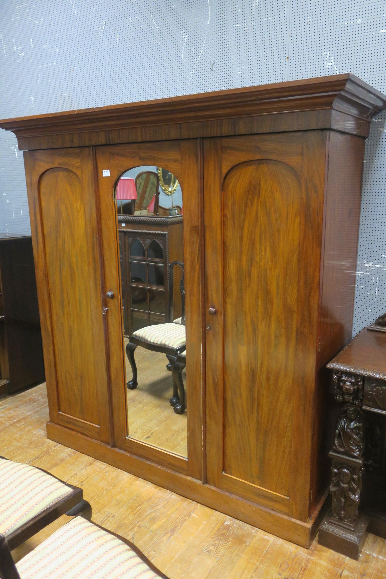 A 19TH CENTURY MAHOGANY THREE DOOR WARDROBE the outset moulded cornice above a central mirrored