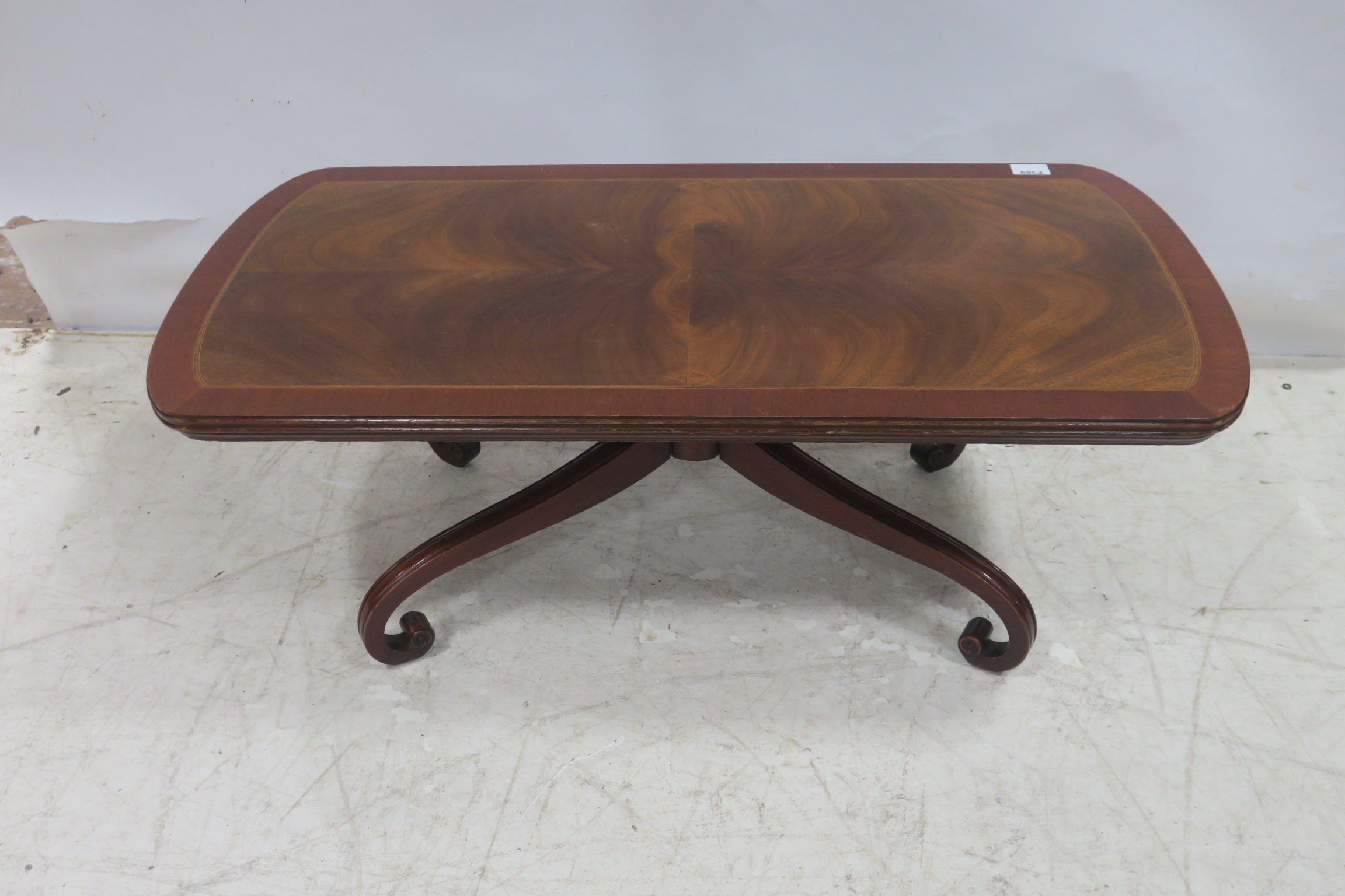 A MAHOGANY CROSS BANDED COFFEE TABLE of rectangular outline with scroll legs 41cm (h) x 112cm (w) x