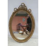 A CONTINENTAL GILT FRAME MIRROR the oval bevelled glass plate within a moulded frame with ribbon