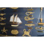 A CASE OF FRAMED KNOTS centred by a sailing ship and stained wood and gilt brass bound frame