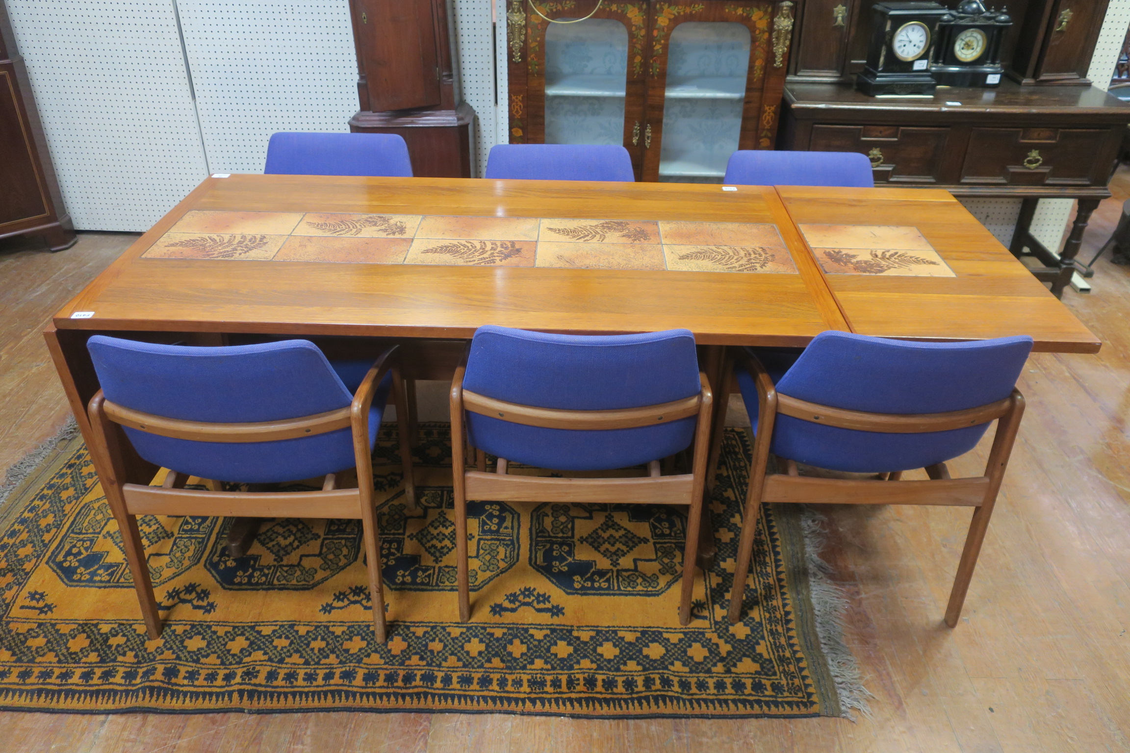 A DANISH TEAK SEVEN PIECE DINING SUITE comprising six upholstered armchairs with moulded arms on