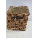 A WICKER LOG BASKET of rectangular form with leather carry handles 59cm x 61cm