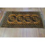A WOOL RUG the mustard ground with central panels filled with palmets hooks and serrated panels