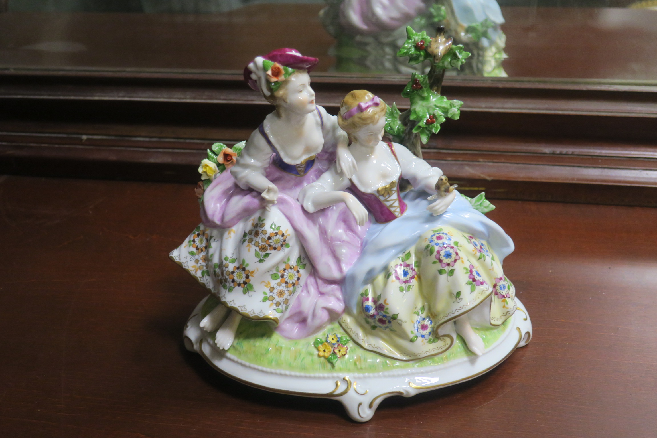 A CONTINENTAL PORCELAIN PAINTED GROUP modelled as two females shown seated on an oval base