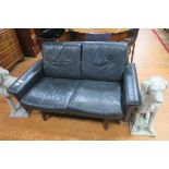 A RETRO BLACK HIDE UPHOLSTERED TWO SEATER SETTEE with loose cushions on cylindrical tapering legs