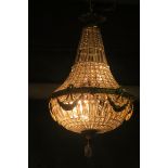 A CONTINENTAL GILT BRASS AND CUT GLASS BASKET CHANDELIER decorated with faceted pendents the