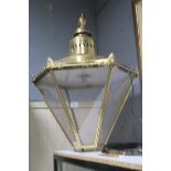A BRASS WALL MOUNTED LANTERN of octagonal tapering form with glazed panels raised on wrought iron