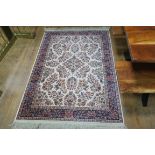 A WOOL RUG the beige ground with central floral panel within a conforming border 200cm x 132cm