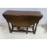 A 19TH CENTURY MAHOGANY DROP LEAF TABLE the oval hinged top raised on square and ring turned
