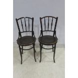A PAIR OF BENTWOOD HIGH CHAIRS each with a curved top rail and spindle splats and shaped seats on