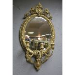 A GIRANDOLE GILT FRAME MIRROR the oval bevelled glass plate with three candle sconces