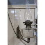 A 19TH CENTURY BRASS WALL MOUNTED OIL LAMP with brass back plate and pierced arm with faceted glass