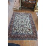 AN ORIENTAL WOOL RUG the beige light blue and wine ground with central floral panel within a