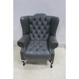 A GREY HIDE UPHOLSTERED WINGED LIBRARY ARM CHAIR with deep buttoned upholstered back and seat with