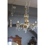 A CONTINENTAL GILT BRASS AND CUT GLASS SIX BRANCH CHANDELIER hung with faceted pendants