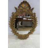 A CONTINENTAL GILT FRAMED MIRROR the oval plate within an acanthus leaf frame with shell cresting
