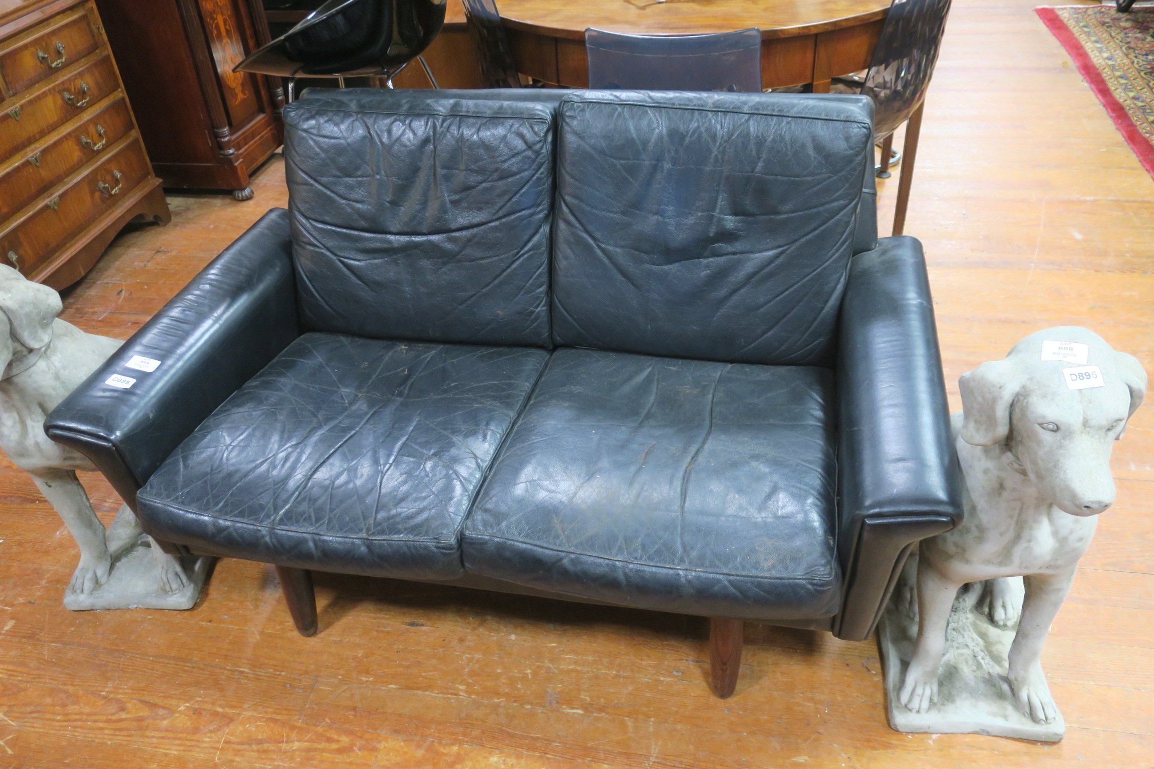 A RETRO BLACK HIDE UPHOLSTERED TWO SEATER SETTEE with loose cushions on cylindrical tapering legs