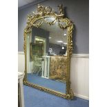A FINE CONTINENTAL GILT FRAMED MIRROR the rectangular arched plate within a bell husk and flower