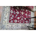 A FINE WOOL RUG the wine and beige ground with central floral panel within a conforming border