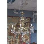 A CONTINENTAL GILT BRASS AND CUT GLASS SIX BRANCH CHANDELIER hung with faceted pendants THE BUYER
