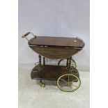 A CONTINENTAL KINGWOOD SERVING TROLLEY the oval hinged top with brass gallery above an under tier