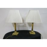 A PAIR OF BRASS CORINTHIAN COLUMN TABLE LAMPS on square stepped base with shades