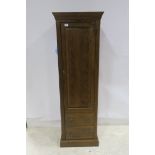 AN OAK CUPBOARD the moulded cornice above a panelled door with mock drawers on platform base 171cm