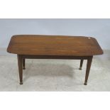 A VINTAGE TEAK COFFEE TABLE of rectangular outline on cylindrical tapering legs with brass caps