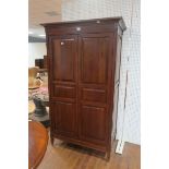 A CHERRYWOOD TWO DOOR WARDROBE the outswept moulded cornice above a pair of panelled doors