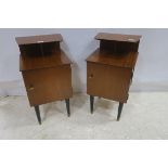 A PAIR OF RETRO TEAK BEDSIDE PEDESTALS each with a stepped top and cupboard on cylindrical tapering