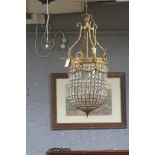 A CONTINENTAL GILT BRASS AND CUT GLASS BASKET CENTRE LIGHT hung with faceted pendants and gilt