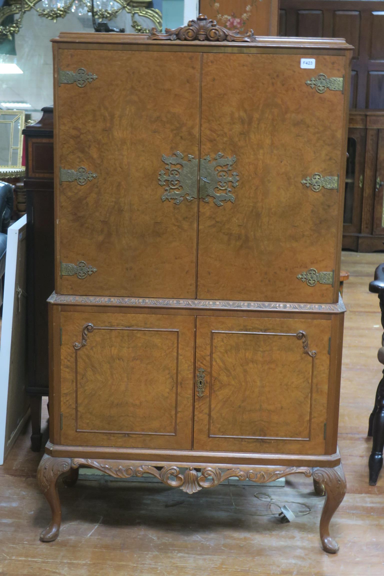 A GOOD VINTAGE WALNUT COCKTAIL CABINET the rectangular top with carved decoration above a pair of