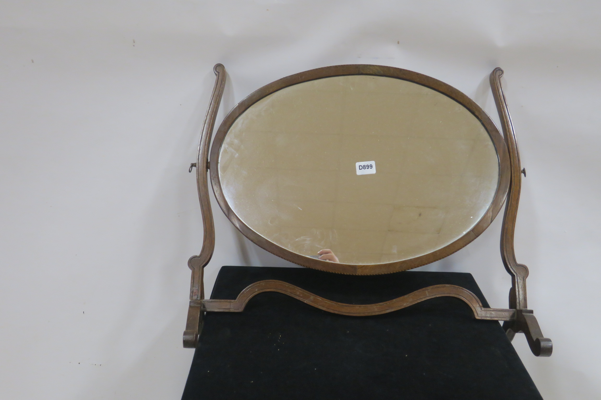 A 19TH CENTURY MAHOGANY CRUTCH FRAME MIRROR of oval outline on moulded stand with scroll legs 57cm
