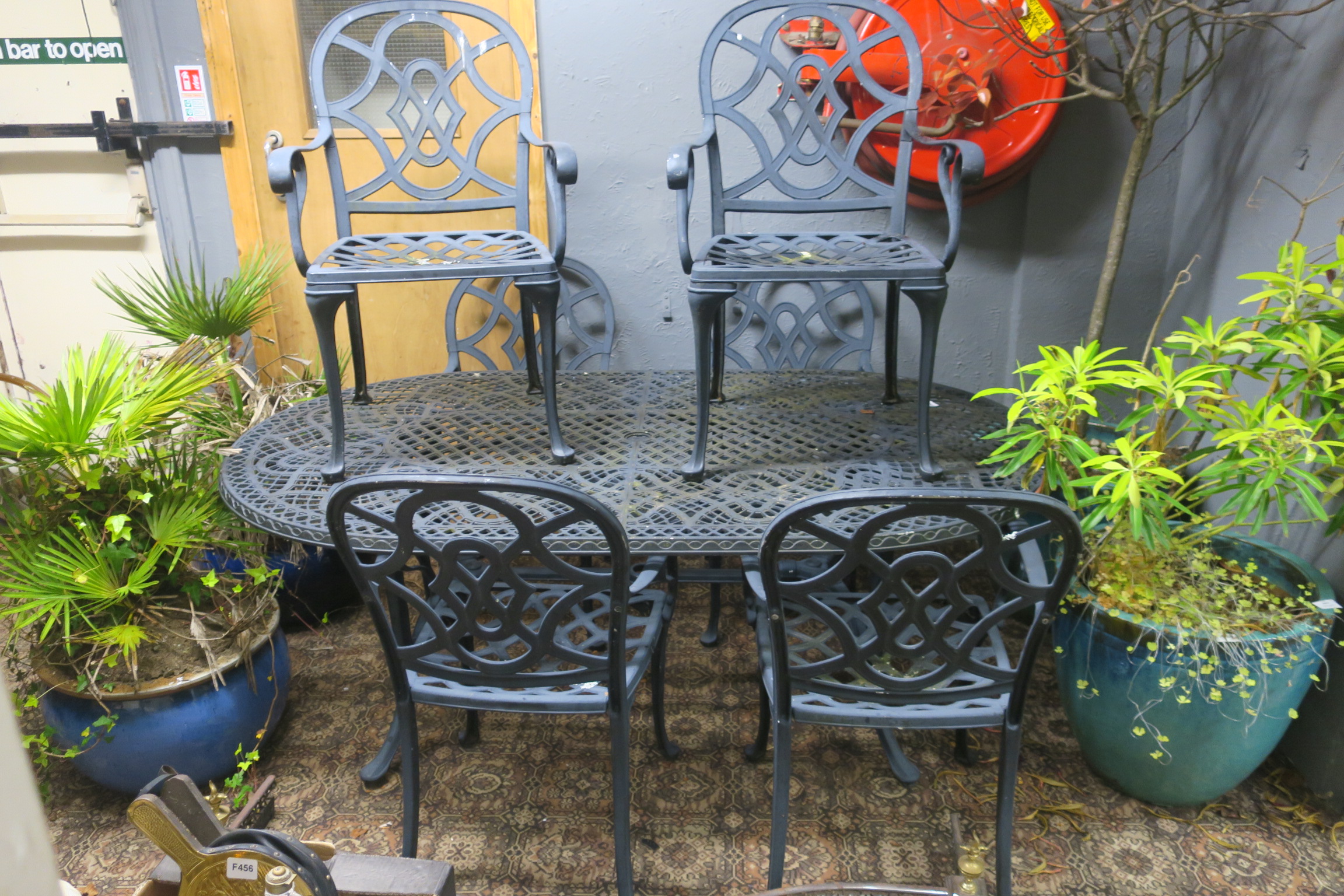 A SEVEN PIECE CAST METAL PATIO SUITE comprising six elbow chairs and table of oval outline on