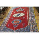 A WOOL RUG the wine and indigo ground with central serrated panel within a conforming border 304cm