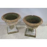 A PAIR OF 19TH CENTURY CAST IRON GARDEN URNS each of semi lobed compana form raised on square