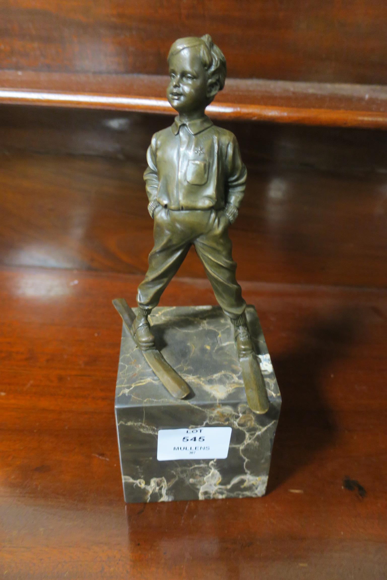 A BRONZED FIGURE modelled as a young boy skiing shown standing on a veined marble base 28cm
