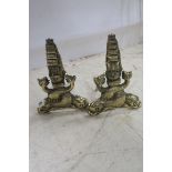 A PAIR OF BRASS FIRE DOGS with ship's mast finial raised on dual dolphin supports inscribed