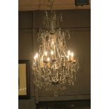 A CONTINENTAL SILVERED AND CUT GLASS TEN BRANCH CHANDELIER hung with faceted pendent drops