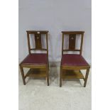 A PAIR OF 1950s OAK CHAIRS each with a moulded top rail above an upholstered seat the back