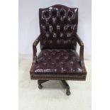 A WINE HIDE UPHOLSTERED SWIVEL OFFICE CHAIR with deep buttoned upholstered back and seat on moulded