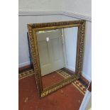 A CONTINENTAL GILT FRAMED MIRROR the rectangular plate within a stylized foliate moulded frame
