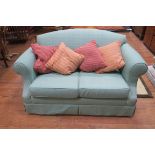 A TWO SEATER SETTEE the shaped back with scroll over arms and loose cushions on pad feet 148cm (w)