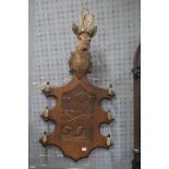 A 19TH CENTURY CARVED OAK WALL MOUNTED COAT RACK surmounted by a deer's head above a shaped carved