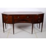 A GEORGIAN MAHOGANY CROSS BANDED SIDEBOARD of rectangular bowed outline the shaped top with frieze