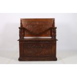 A CARVED OAK MONKS BENCH the rectangular hinged top with hinged seat and moulded arm rests raised