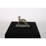 AN ART DECO DESIGN METAL AND POLYCHROME FIGURE modelled as a greyhound shown standing on a marble