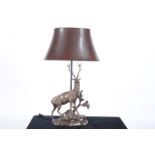 A COLDCAST FIGURAL TABLE LAMP modelled as a deer shown standing on a rock work base with shade 82cm