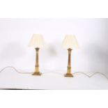 A PAIR OF BRASS TABLE LAMPS each with reeded column above a square stepped base with pleated shades