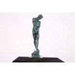 A GREEN PATINATED BRONZE FIGURE modelled as a male shown standing on a rock work base and marble